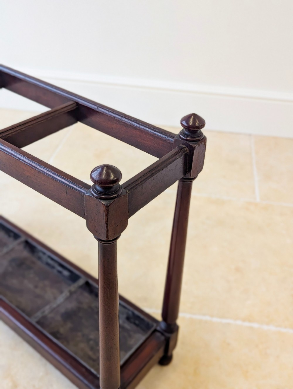 A Victorian dark mahogany stick stand featuring four turned corner supports, a partitioned upper frame, and a metal drip tray base. View XVII