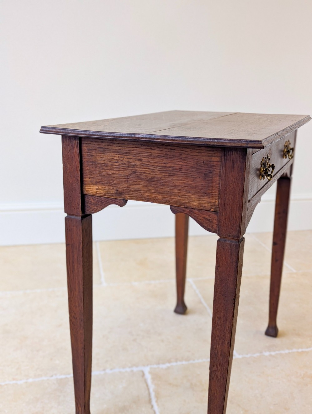An antique dark oak side table featuring a single drawer with brass drop handles, shaped corner aprons, and slender tapered legs. View XI