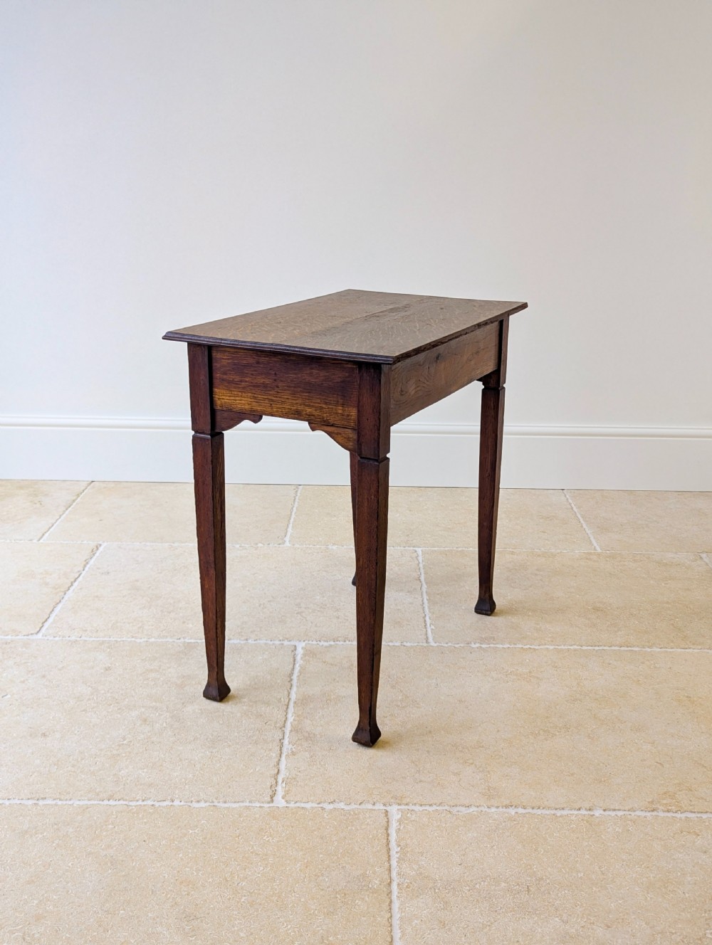 An antique dark oak side table featuring a single drawer with brass drop handles, shaped corner aprons, and slender tapered legs. View XV