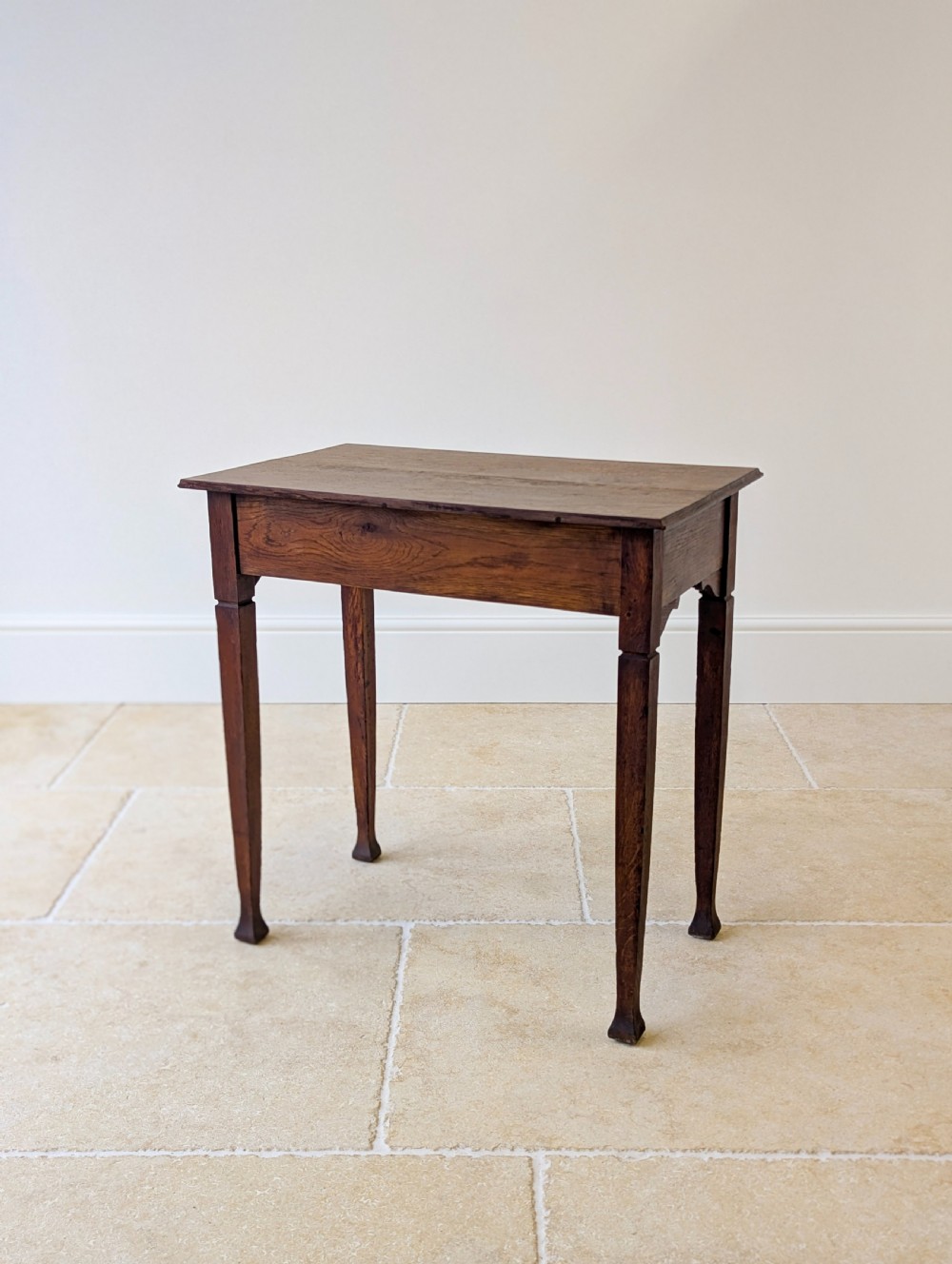 An antique dark oak side table featuring a single drawer with brass drop handles, shaped corner aprons, and slender tapered legs. View XVI