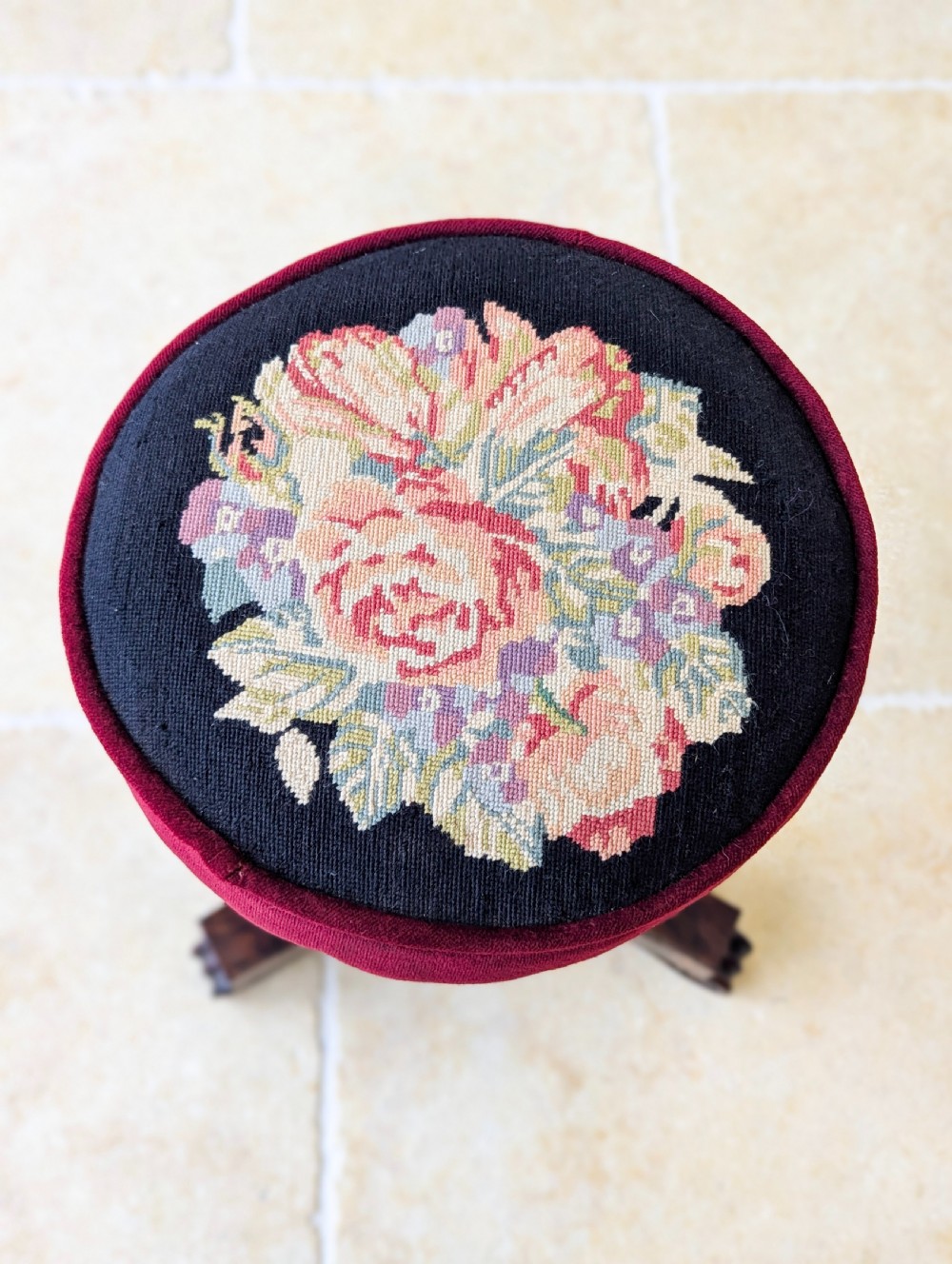 A William IV rosewood adjustable piano stool featuring a circular floral needlepoint seat with burgundy velvet trim, supported by a carved pedestal and triform base. View III