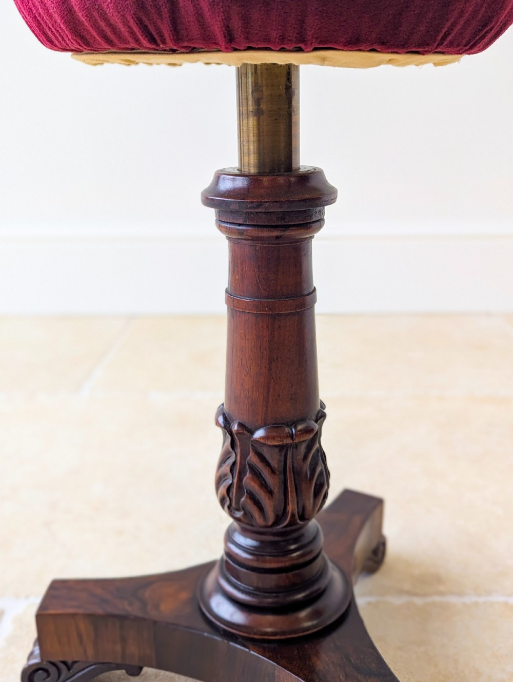 A William IV rosewood adjustable piano stool featuring a circular floral needlepoint seat with burgundy velvet trim, supported by a carved pedestal and triform base. View X