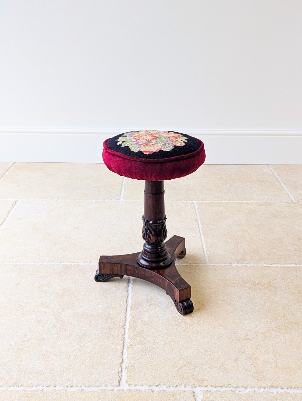 A William IV rosewood adjustable piano stool featuring a circular floral needlepoint seat with burgundy velvet trim, supported by a carved pedestal and triform base. View XIII