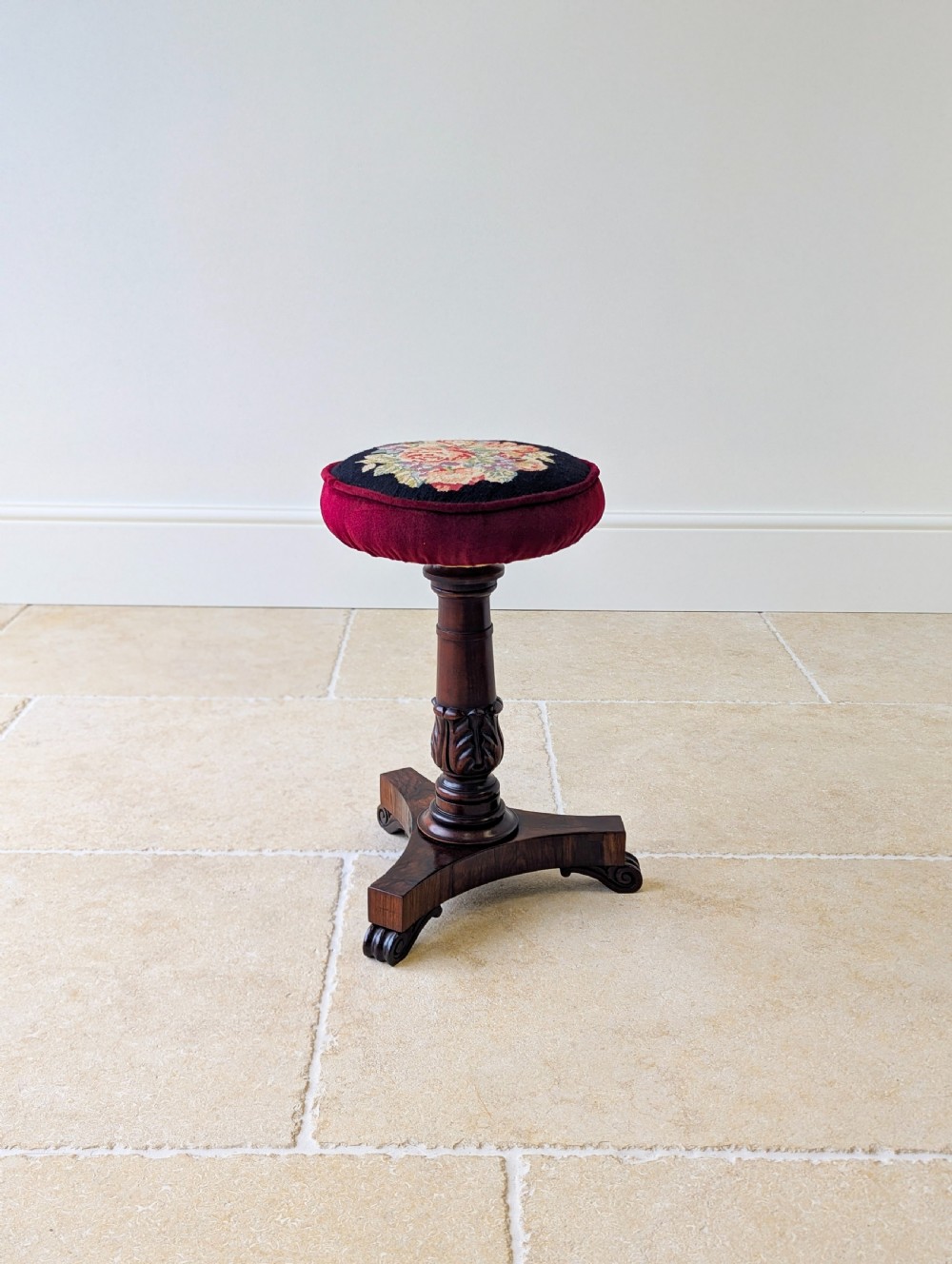 A William IV rosewood adjustable piano stool featuring a circular floral needlepoint seat with burgundy velvet trim, supported by a carved pedestal and triform base. View XV