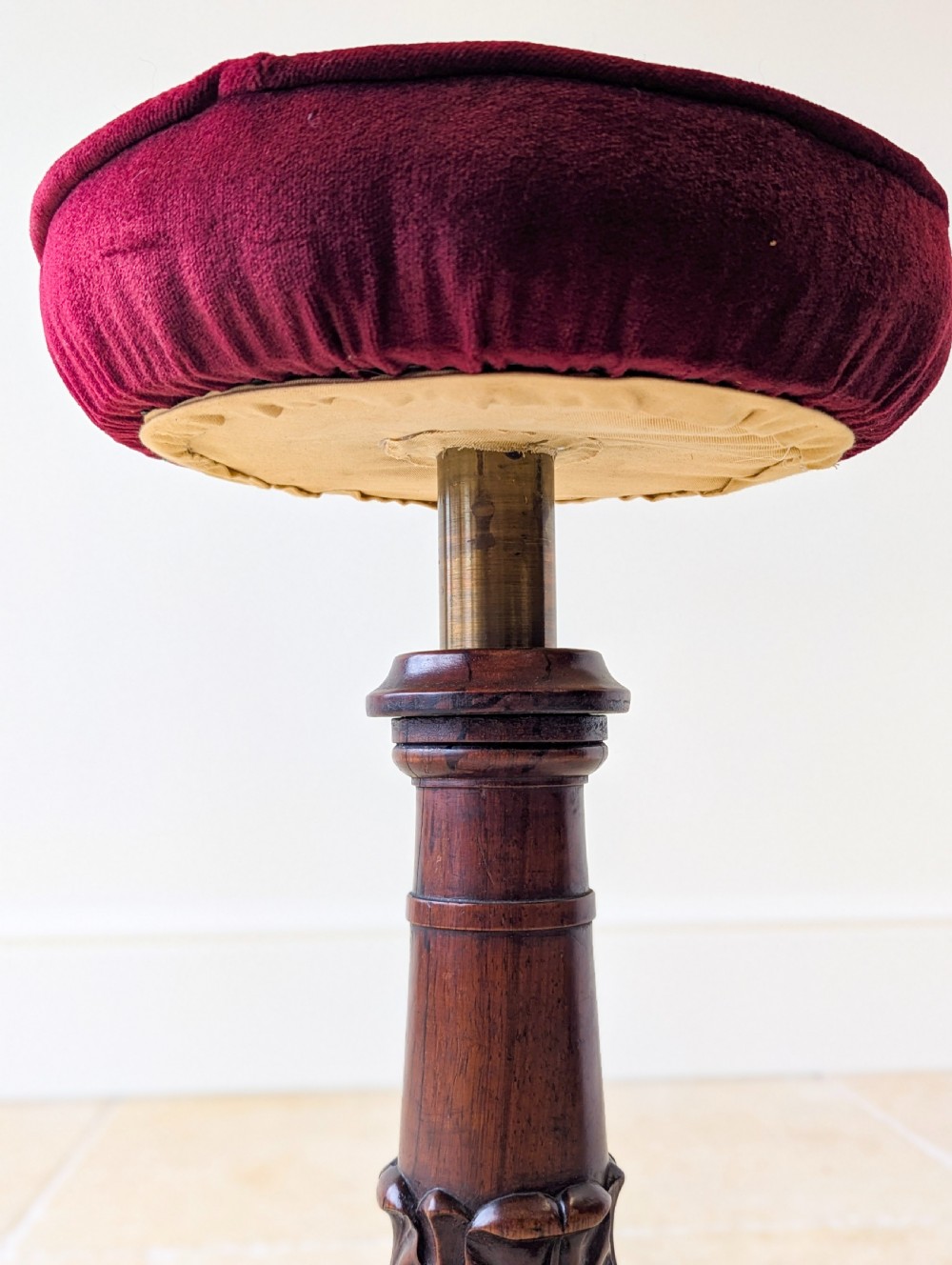 A William IV rosewood adjustable piano stool featuring a circular floral needlepoint seat with burgundy velvet trim, supported by a carved pedestal and triform base. View XVI