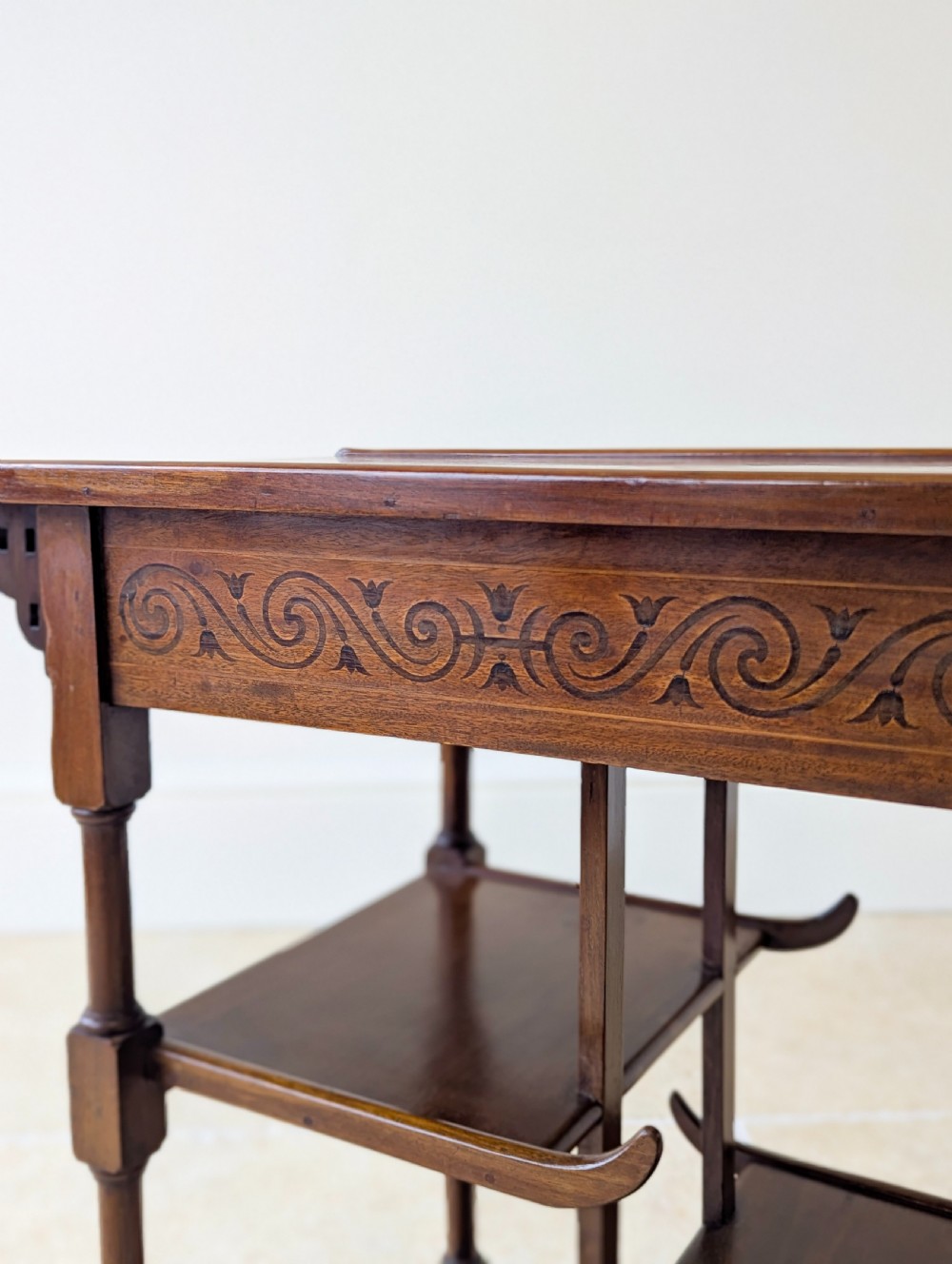 An Edwardian mahogany Anglo-Japanese occasional table with a pagoda-style top, carved scroll apron, and tiered display shelves on turned legs. View IV