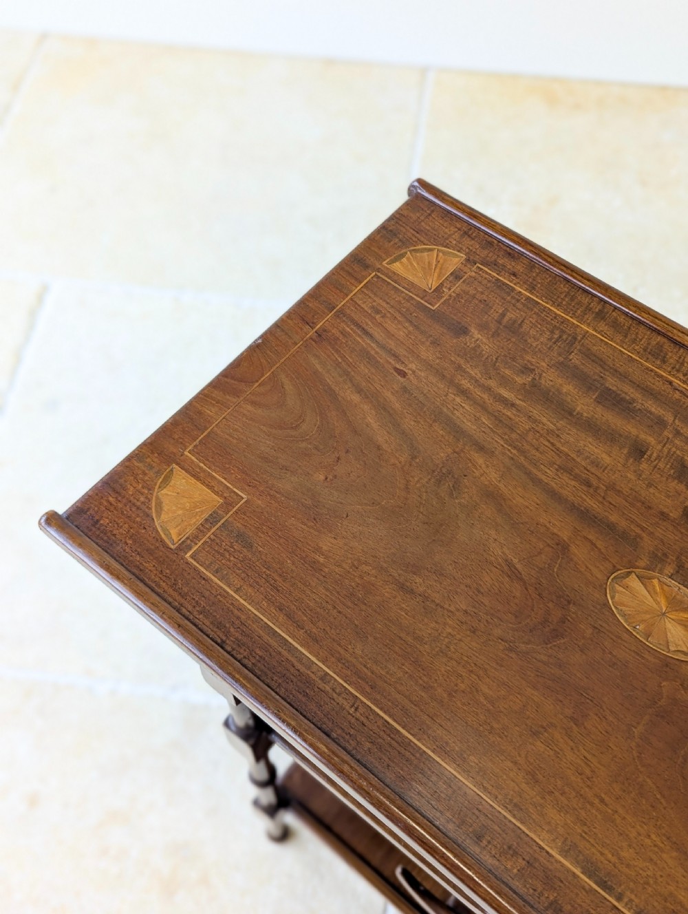 An Edwardian mahogany Anglo-Japanese occasional table with a pagoda-style top, carved scroll apron, and tiered display shelves on turned legs. View VI