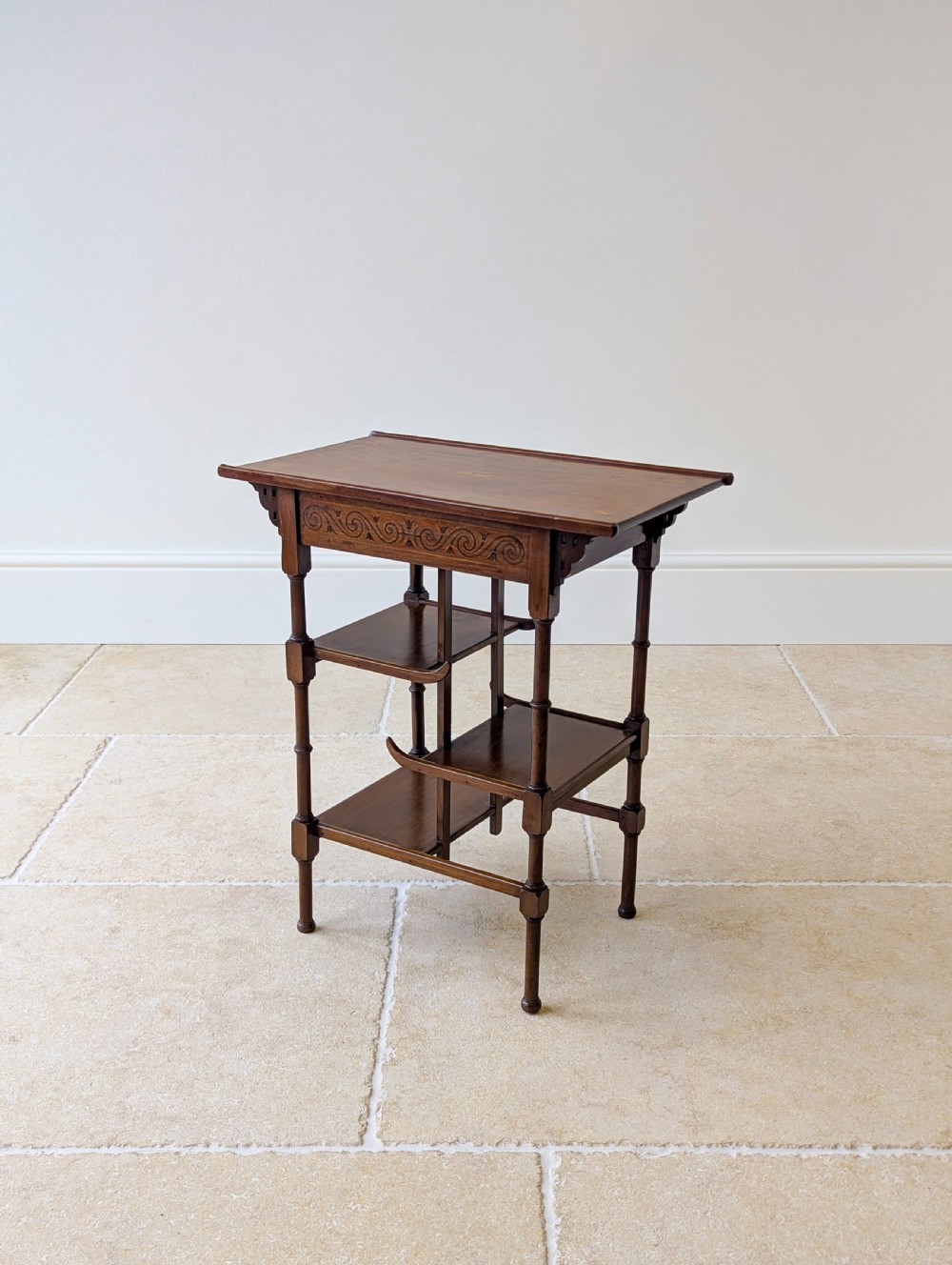 An Edwardian mahogany Anglo-Japanese occasional table with a pagoda-style top, carved scroll apron, and tiered display shelves on turned legs. View X