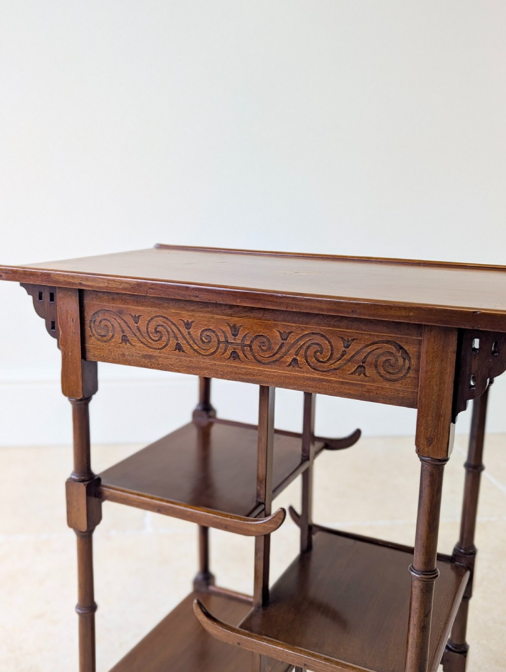 An Edwardian mahogany Anglo-Japanese occasional table with a pagoda-style top, carved scroll apron, and tiered display shelves on turned legs. View XI