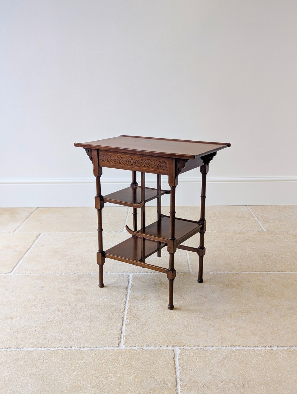 An Edwardian mahogany Anglo-Japanese occasional table with a pagoda-style top, carved scroll apron, and tiered display shelves on turned legs. View XIII