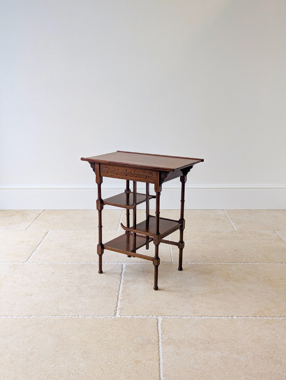 An Edwardian mahogany Anglo-Japanese occasional table with a pagoda-style top, carved scroll apron, and tiered display shelves on turned legs. View XVI