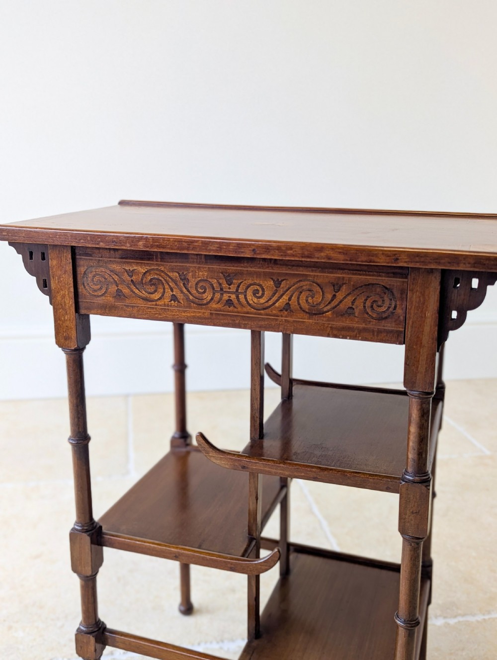 An Edwardian mahogany Anglo-Japanese occasional table with a pagoda-style top, carved scroll apron, and tiered display shelves on turned legs. View XVII