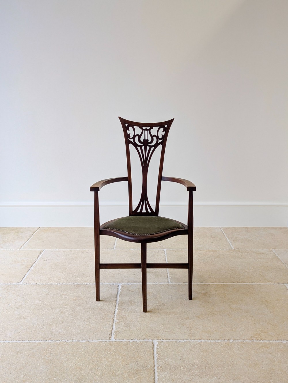 An Edwardian mahogany elbow chair featuring a high pierced back splat, swept arms, and an olive green velvet upholstered seat. View II