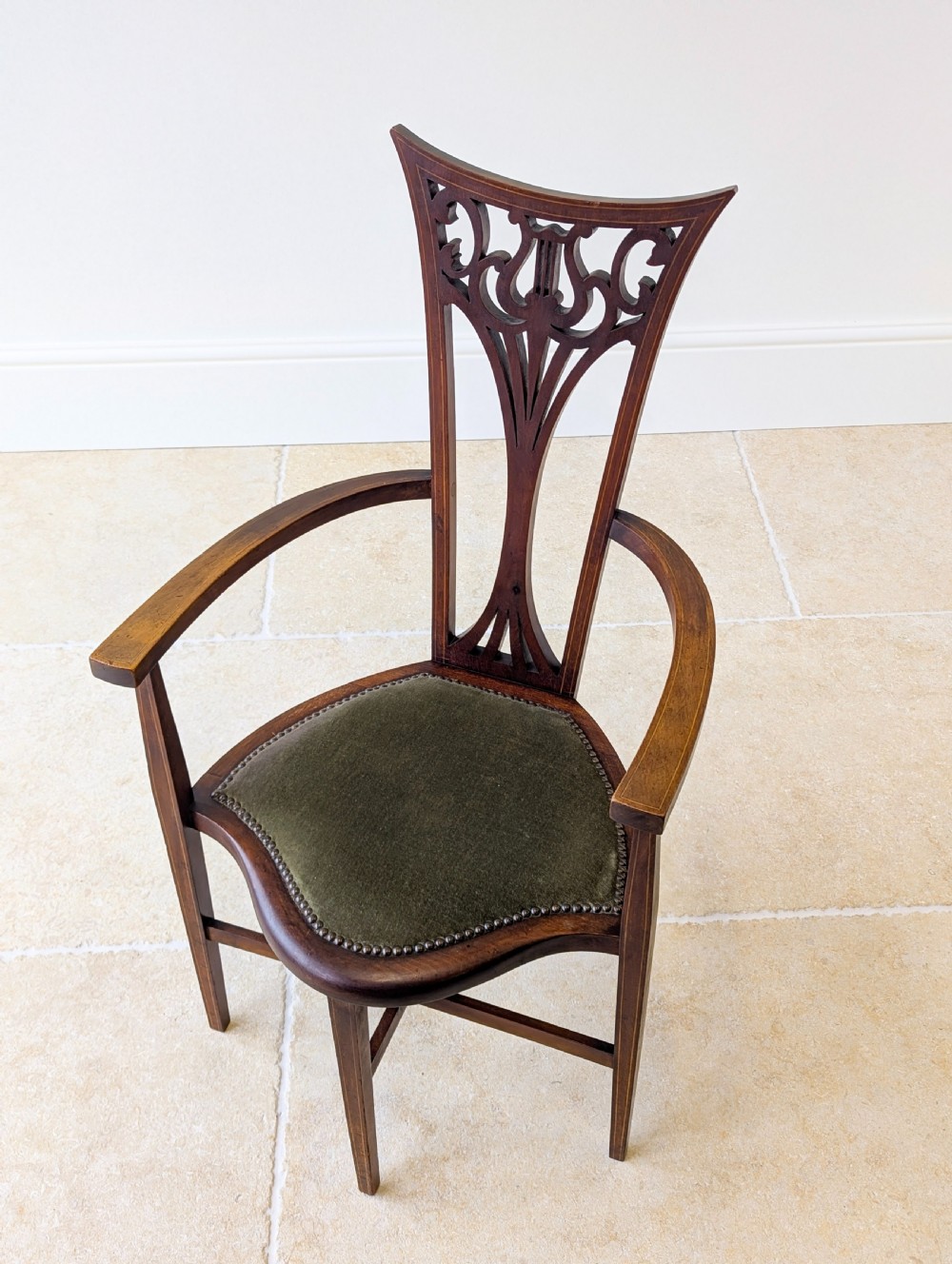 An Edwardian mahogany elbow chair featuring a high pierced back splat, swept arms, and an olive green velvet upholstered seat. View III