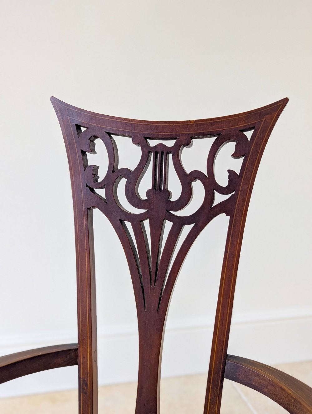 An Edwardian mahogany elbow chair featuring a high pierced back splat, swept arms, and an olive green velvet upholstered seat. View IV