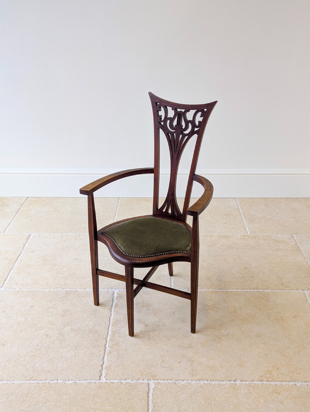 An Edwardian mahogany elbow chair featuring a high pierced back splat, swept arms, and an olive green velvet upholstered seat. View VIII