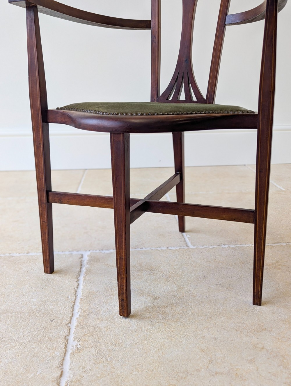 An Edwardian mahogany elbow chair featuring a high pierced back splat, swept arms, and an olive green velvet upholstered seat. View IX
