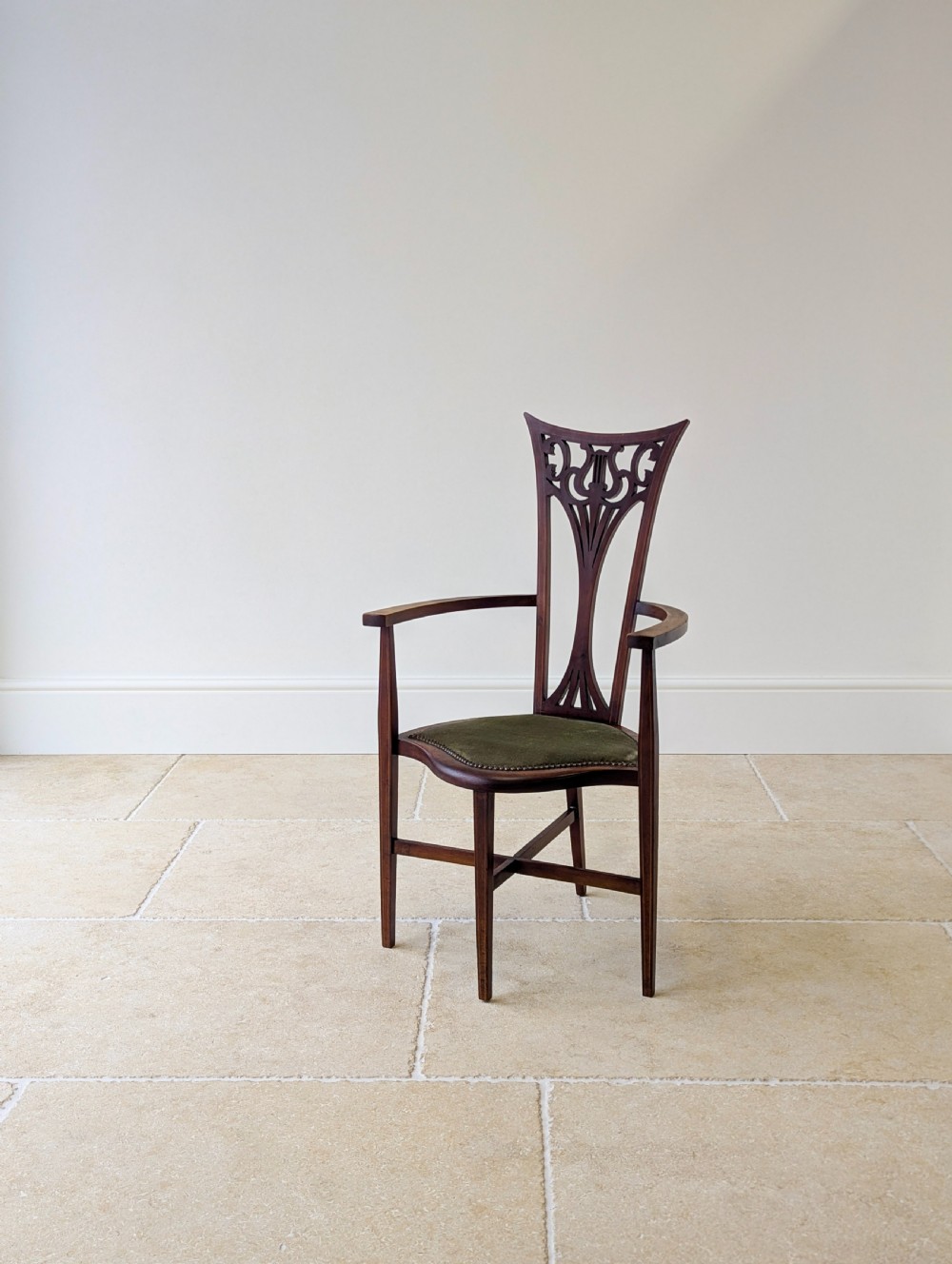 An Edwardian mahogany elbow chair featuring a high pierced back splat, swept arms, and an olive green velvet upholstered seat. View XII