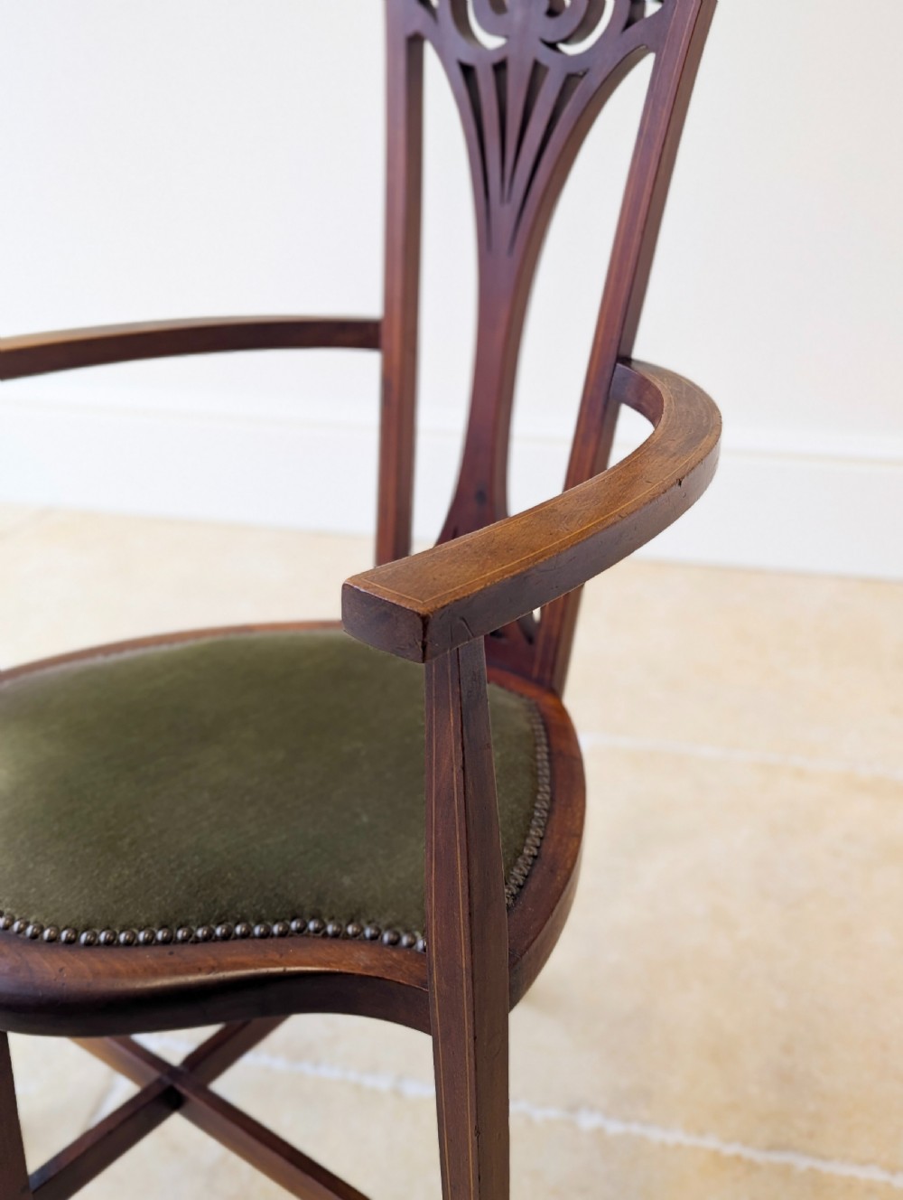 An Edwardian mahogany elbow chair featuring a high pierced back splat, swept arms, and an olive green velvet upholstered seat. View XIII