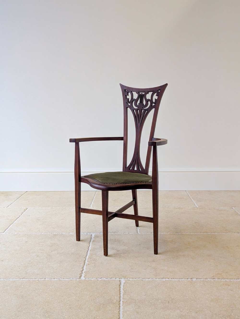 An Edwardian mahogany elbow chair featuring a high pierced back splat, swept arms, and an olive green velvet upholstered seat. View XIV