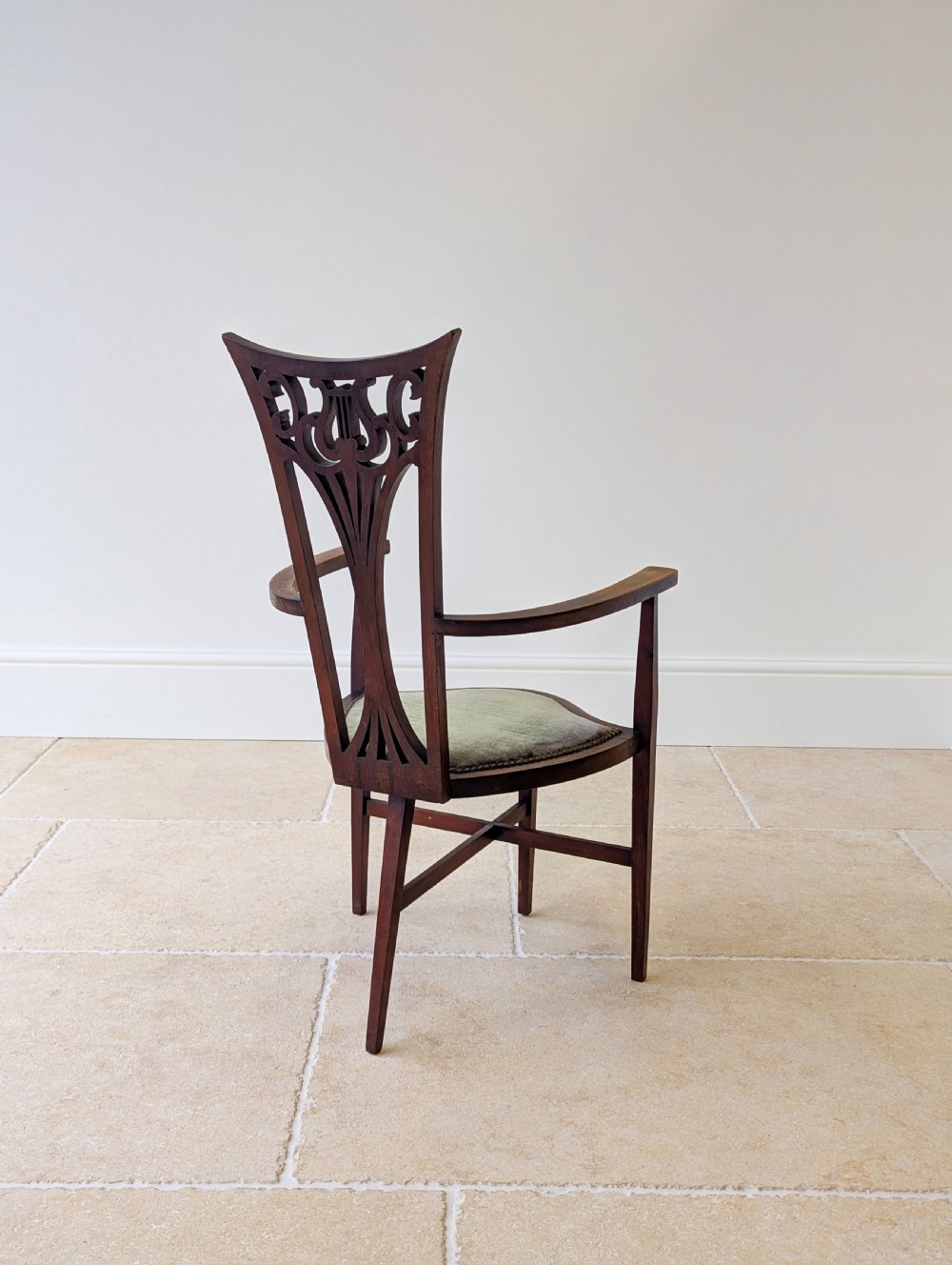 An Edwardian mahogany elbow chair featuring a high pierced back splat, swept arms, and an olive green velvet upholstered seat. View XVII