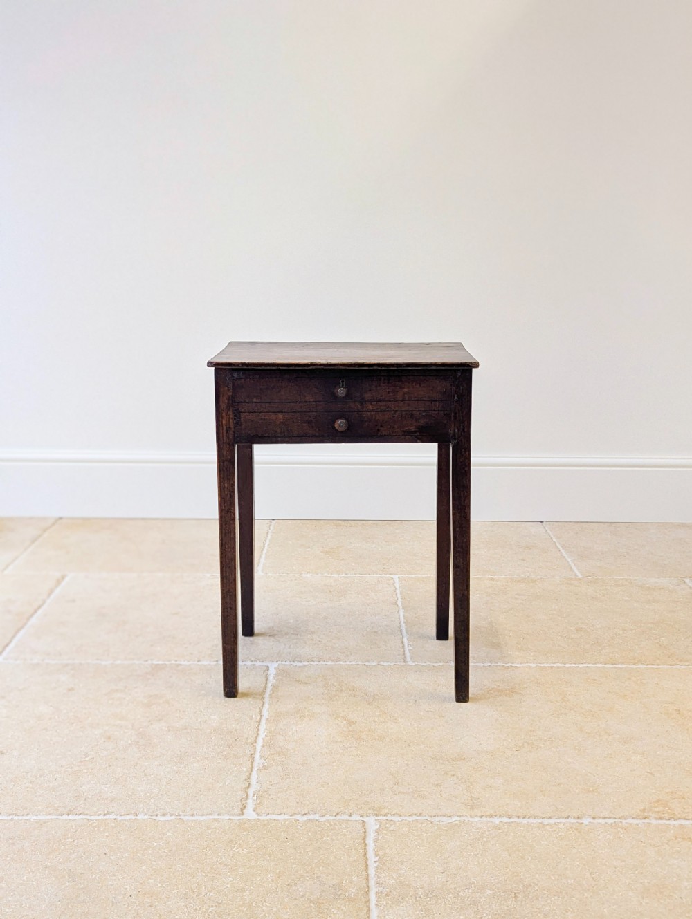 An antique Georgian dark oak work table featuring two drawers, straight square legs, and a rectangular top surface.