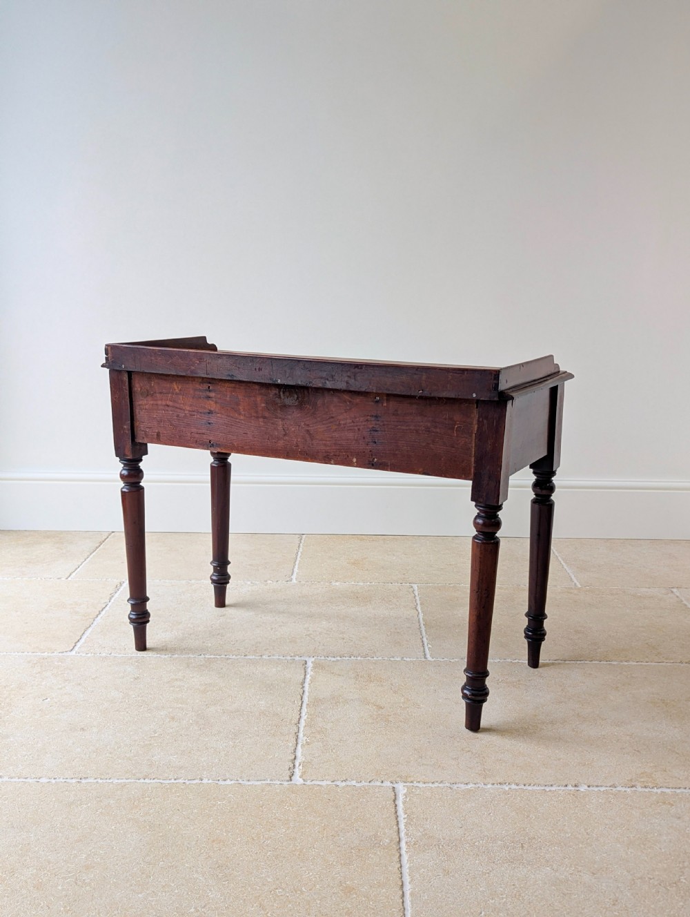 A late Victorian mahogany writing table featuring a low gallery top, three frieze drawers with turned wooden knobs, an arched kneehole, and four turned legs. View XVII