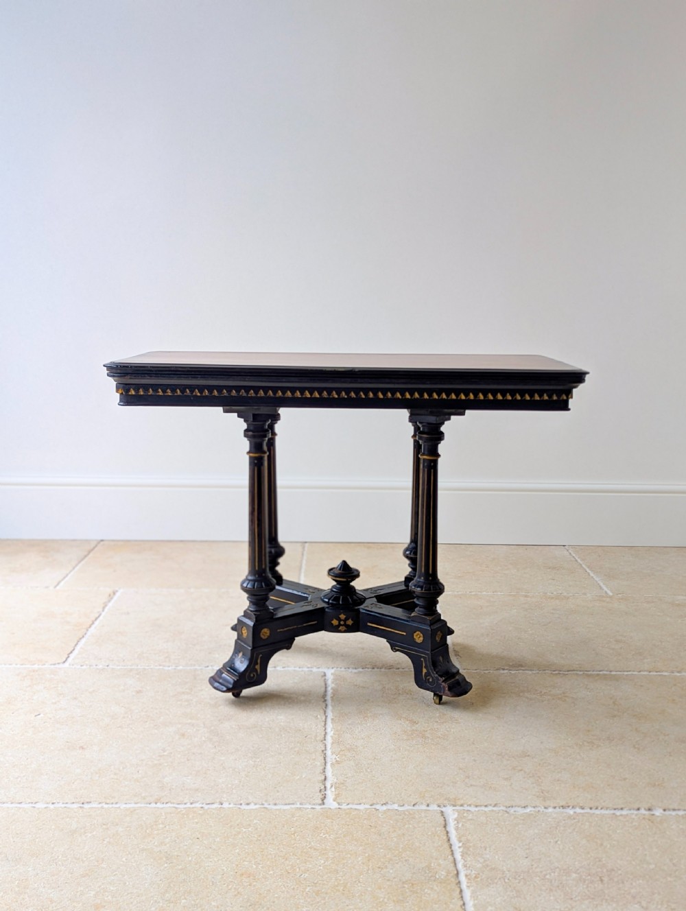 An antique Victorian ebonised and gilt card table with turned twin pedestals and a central finial stretcher.