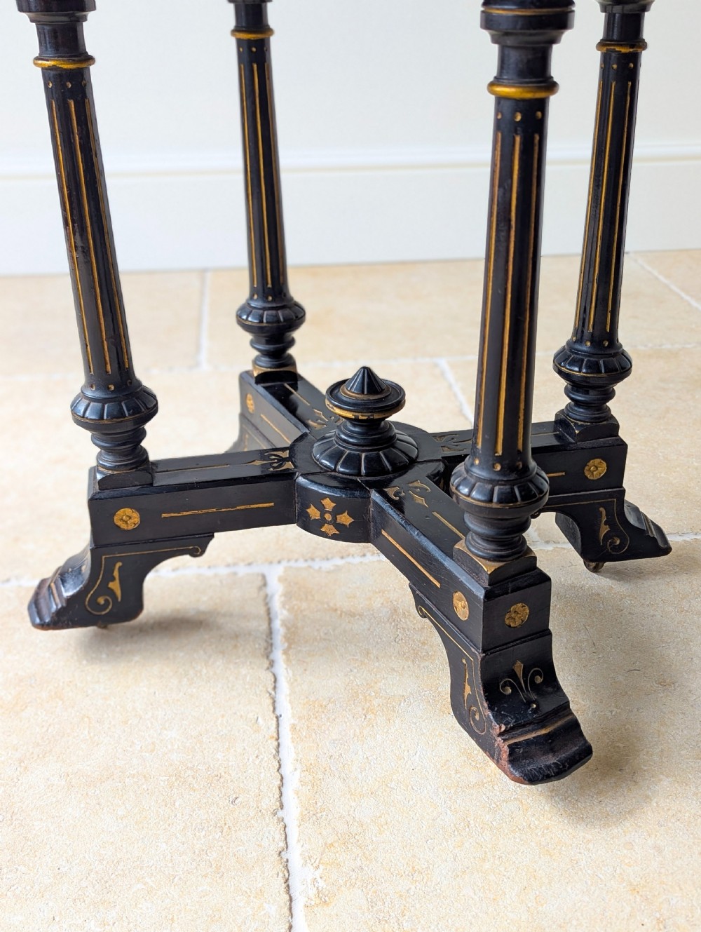 An antique Victorian ebonised and gilt card table with turned twin pedestals and a central finial stretcher. View IV