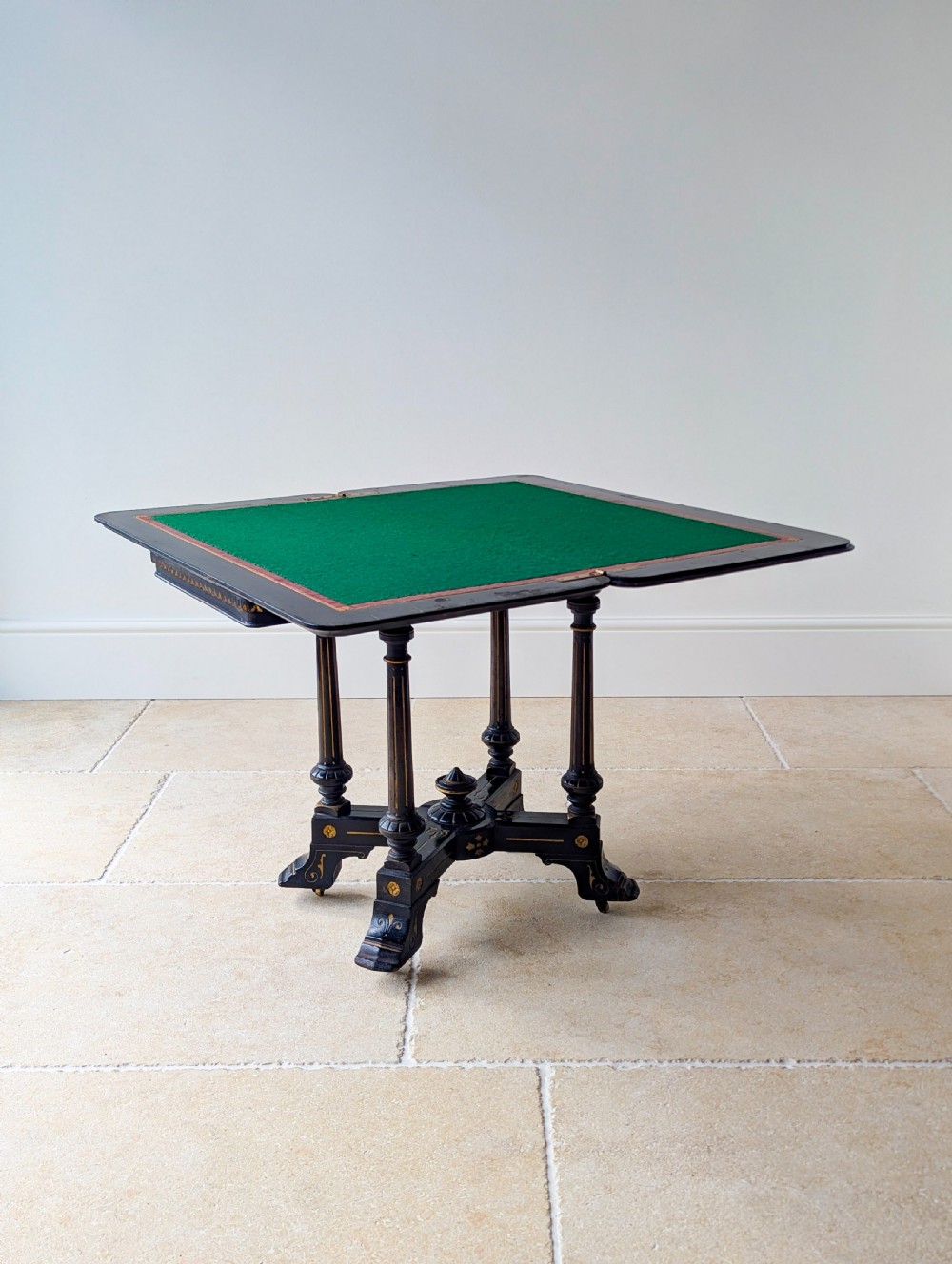 An antique Victorian ebonised and gilt card table with turned twin pedestals and a central finial stretcher. View XIII