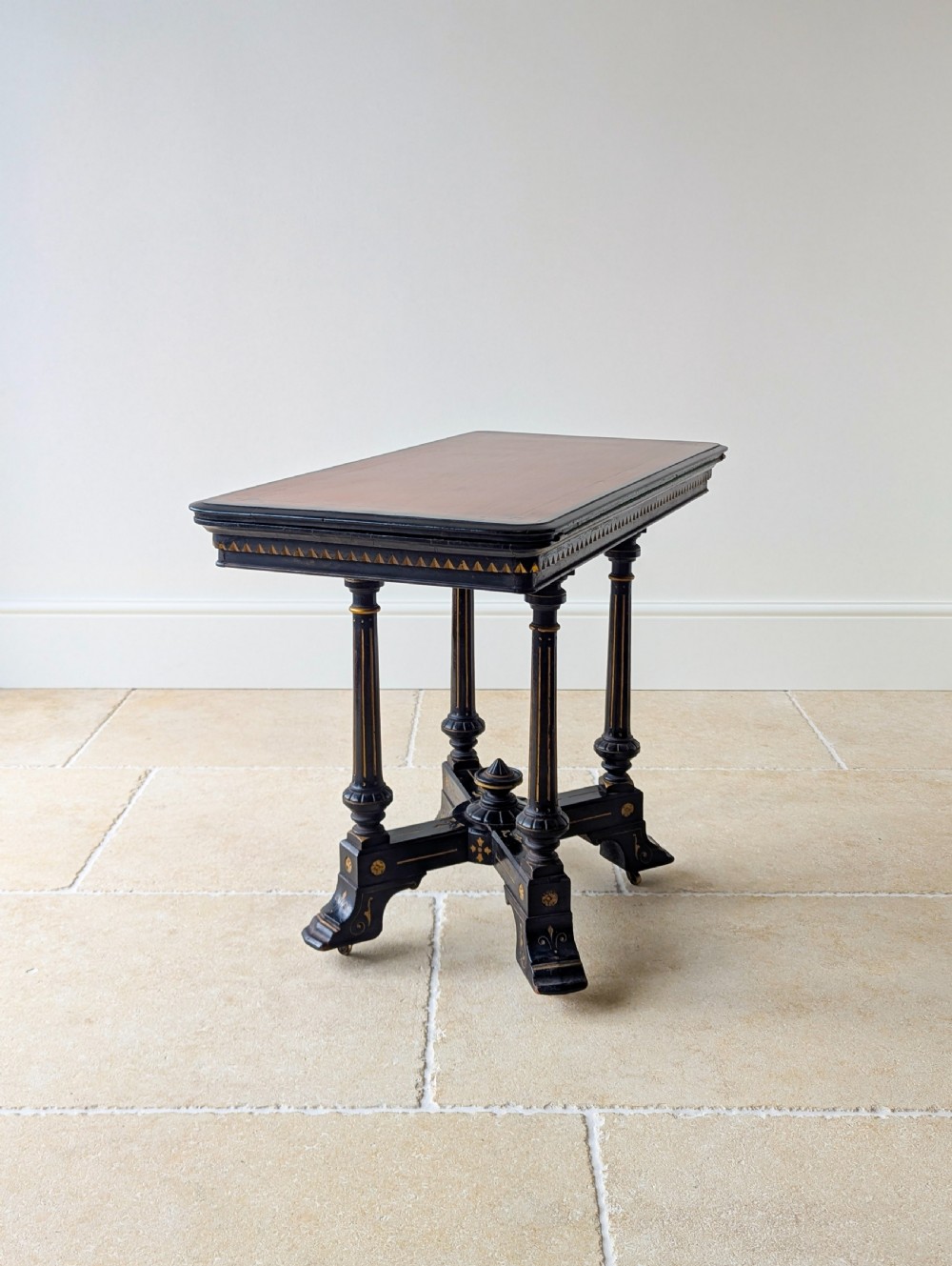 An antique Victorian ebonised and gilt card table with turned twin pedestals and a central finial stretcher. View XIX