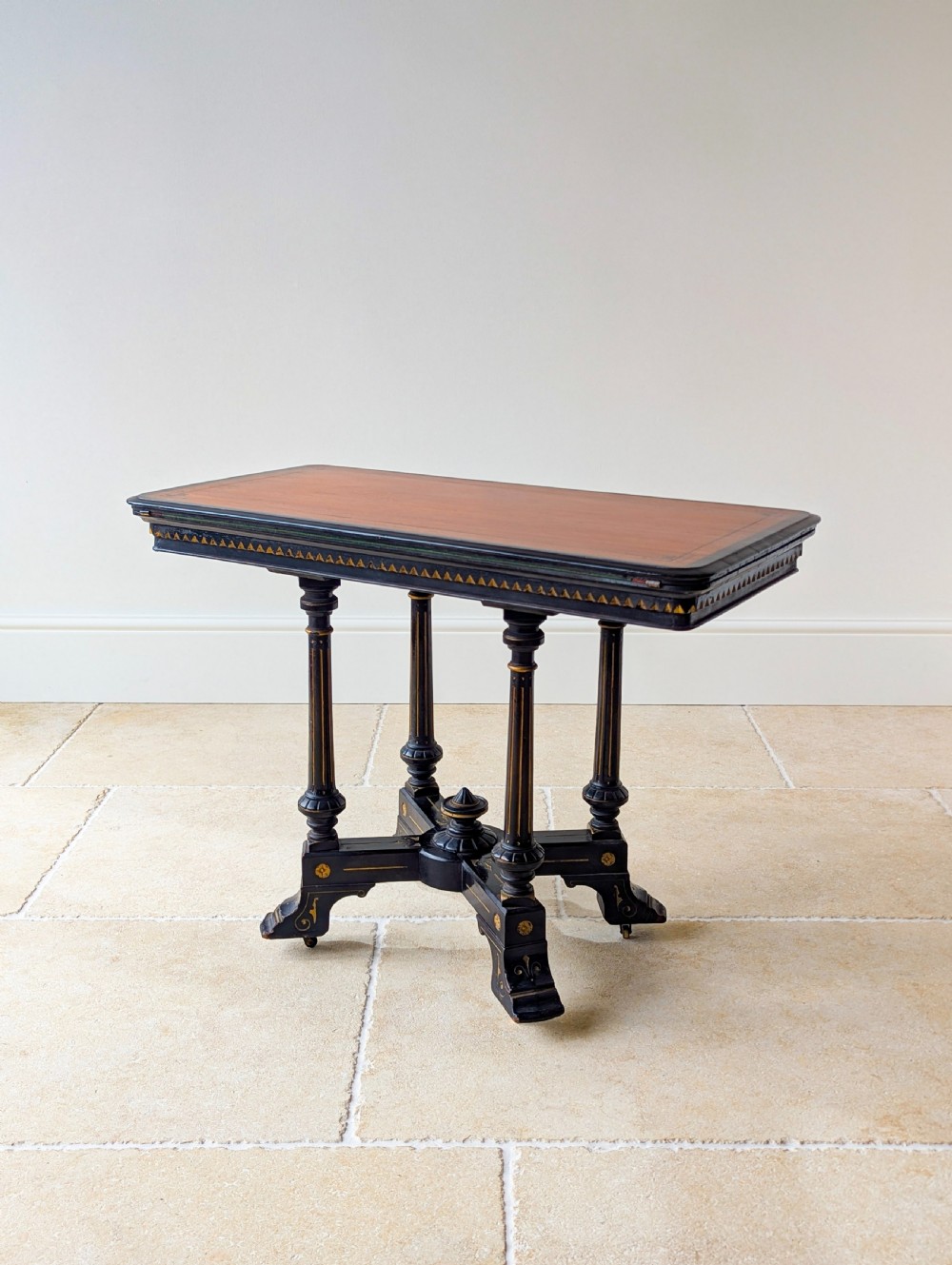 An antique Victorian ebonised and gilt card table with turned twin pedestals and a central finial stretcher. View XX