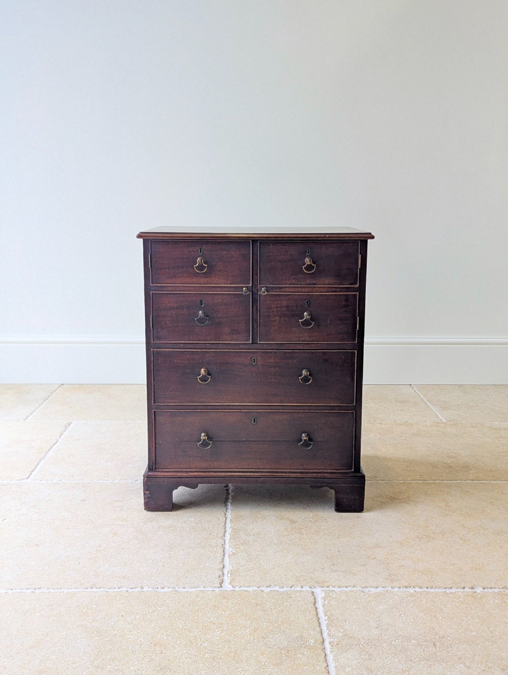 A dark mahogany Georgian commode chest with faux upper drawer fronts, two lower drawers, brass drop handles, and bracket feet. View III