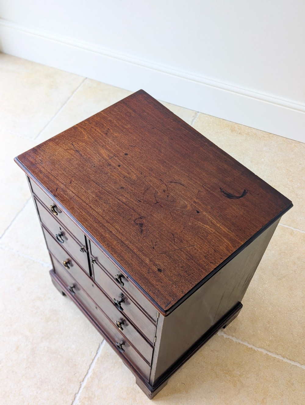 A dark mahogany Georgian commode chest with faux upper drawer fronts, two lower drawers, brass drop handles, and bracket feet. View IV