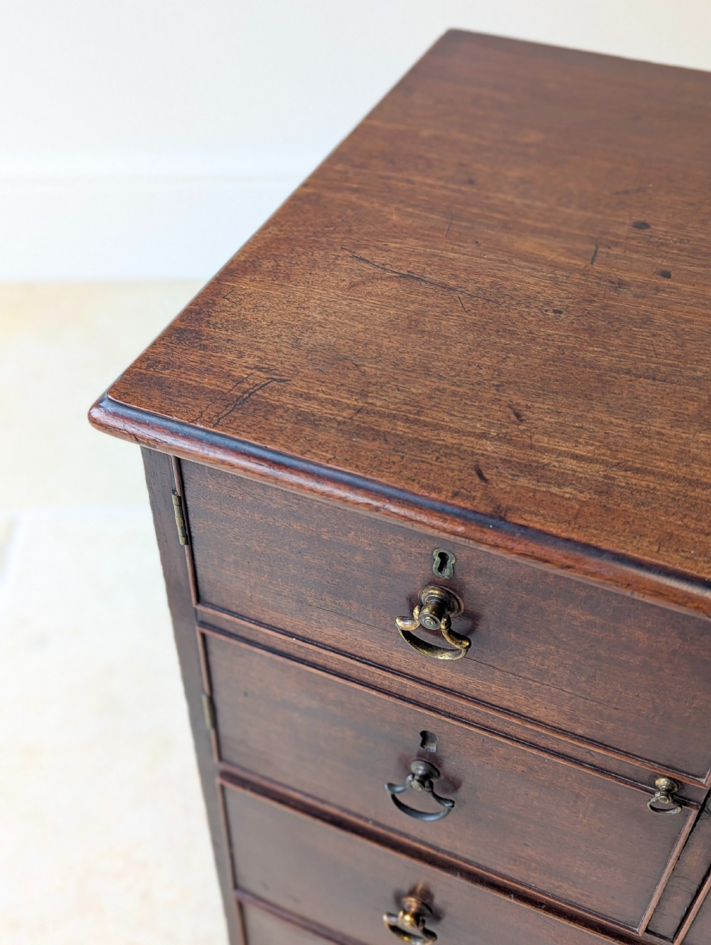 A dark mahogany Georgian commode chest with faux upper drawer fronts, two lower drawers, brass drop handles, and bracket feet. View VI