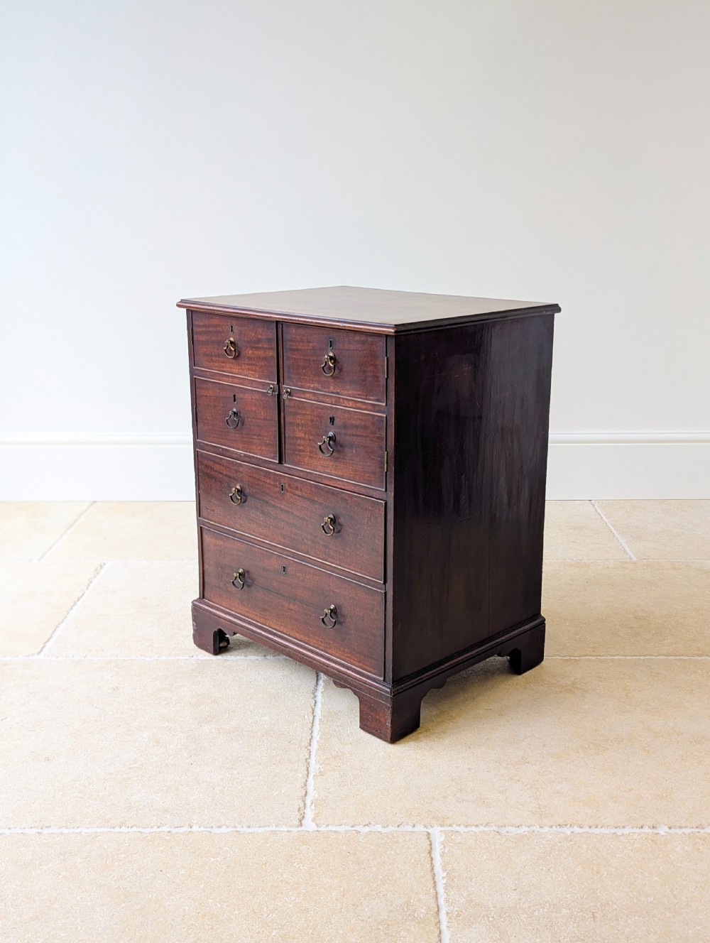 A dark mahogany Georgian commode chest with faux upper drawer fronts, two lower drawers, brass drop handles, and bracket feet. View IX