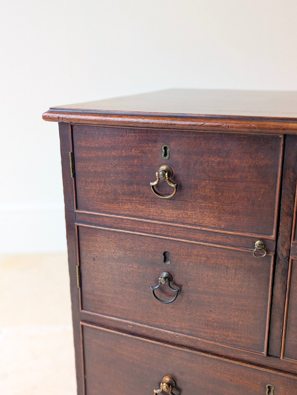 A dark mahogany Georgian commode chest with faux upper drawer fronts, two lower drawers, brass drop handles, and bracket feet. View X