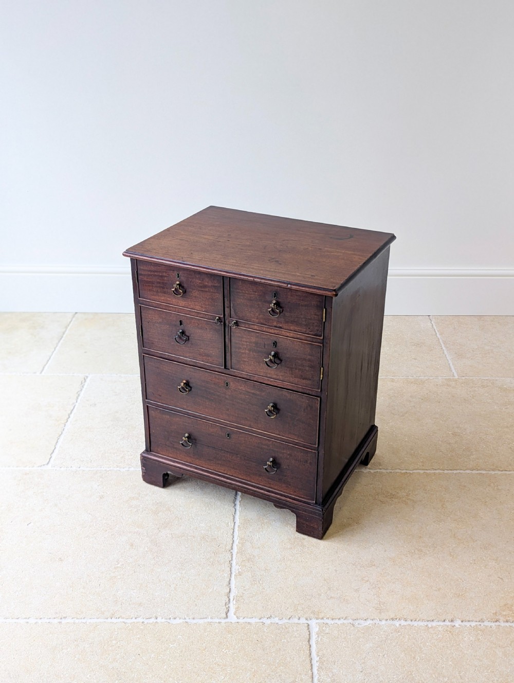 A dark mahogany Georgian commode chest with faux upper drawer fronts, two lower drawers, brass drop handles, and bracket feet. View XI