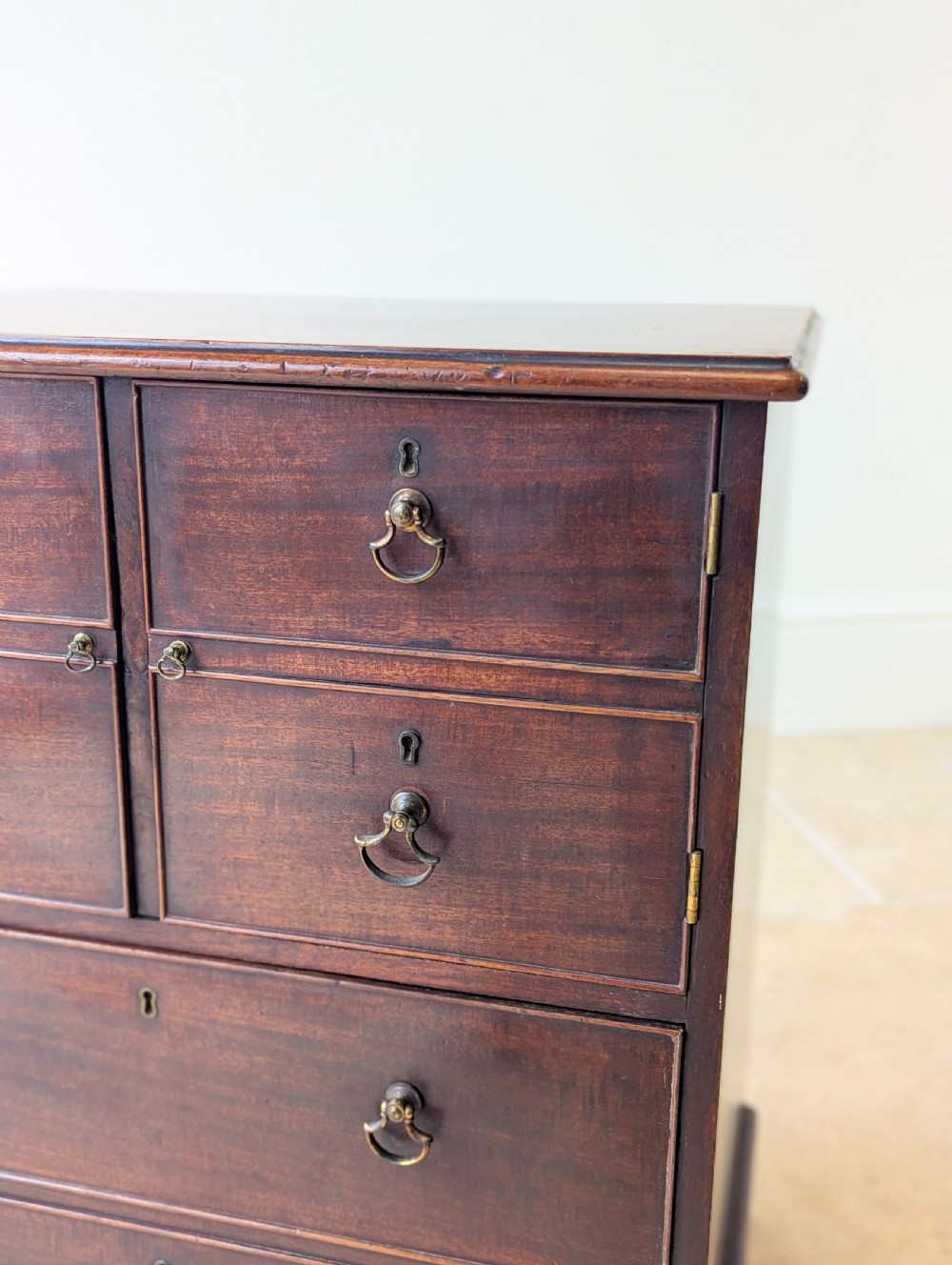 A dark mahogany Georgian commode chest with faux upper drawer fronts, two lower drawers, brass drop handles, and bracket feet. View XIII