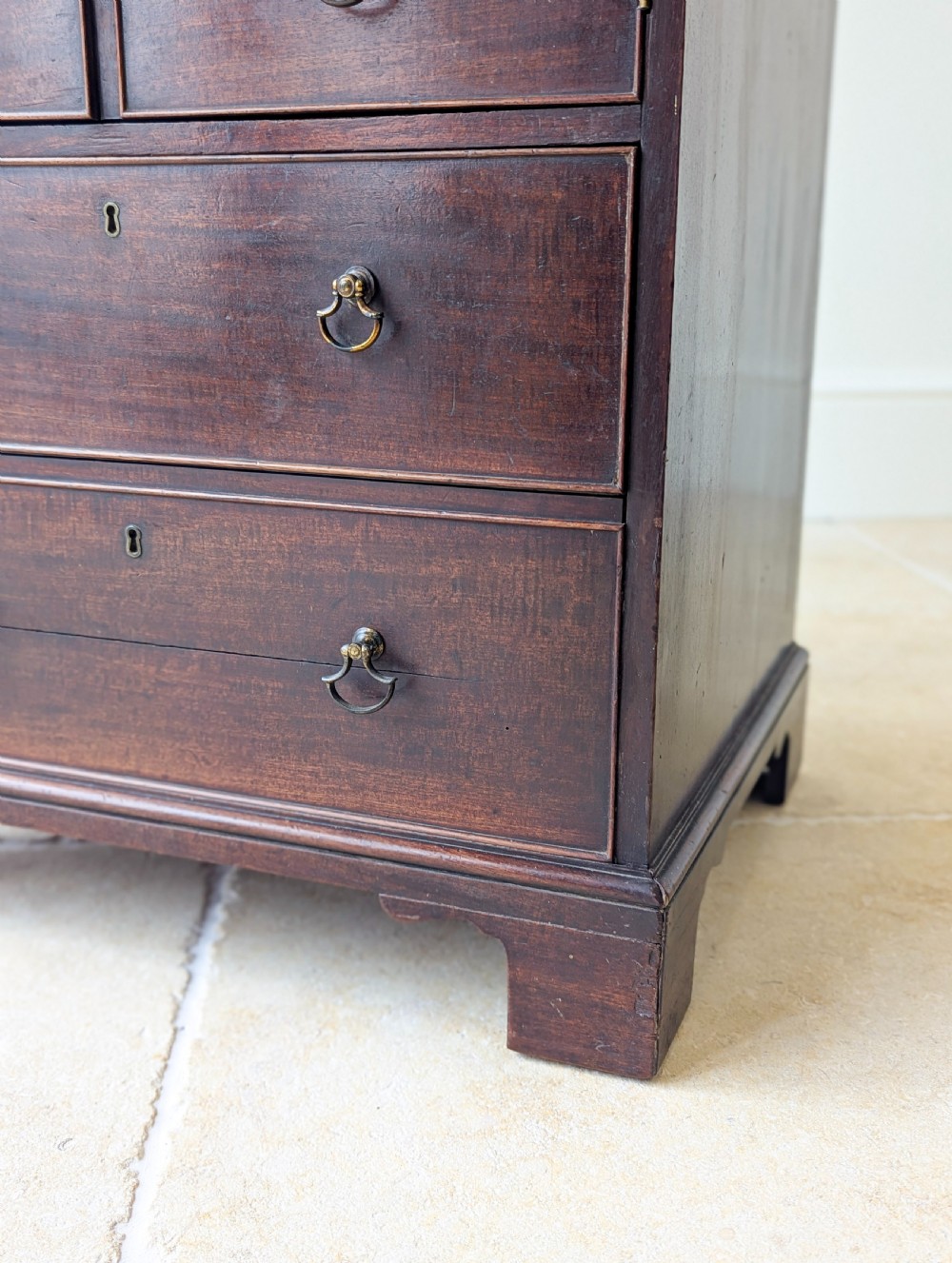 A dark mahogany Georgian commode chest with faux upper drawer fronts, two lower drawers, brass drop handles, and bracket feet. View XV