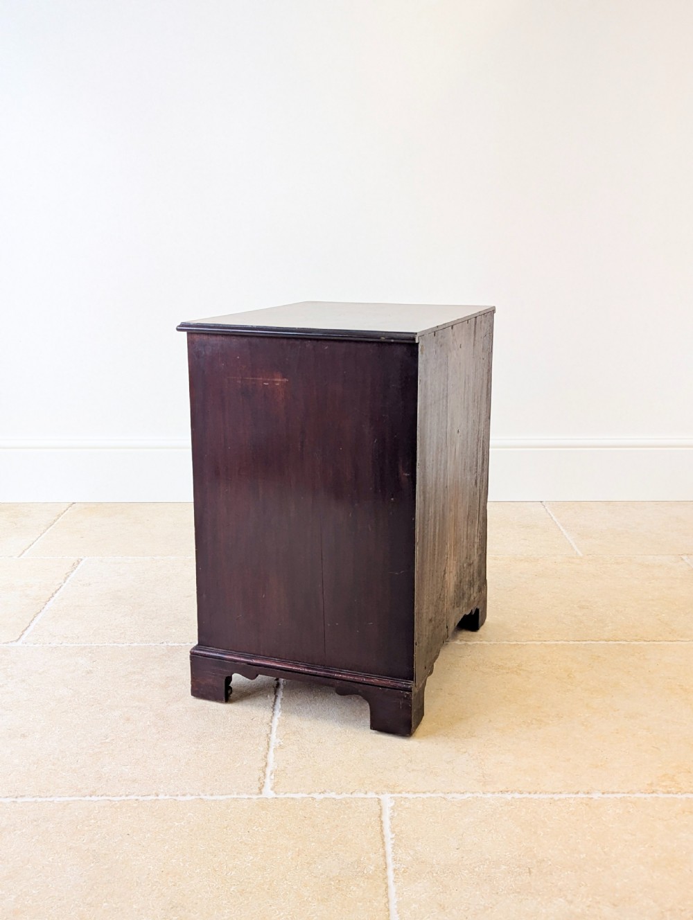 A dark mahogany Georgian commode chest with faux upper drawer fronts, two lower drawers, brass drop handles, and bracket feet. View XVII