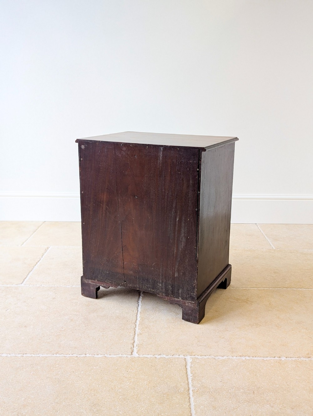 A dark mahogany Georgian commode chest with faux upper drawer fronts, two lower drawers, brass drop handles, and bracket feet. View XVIII