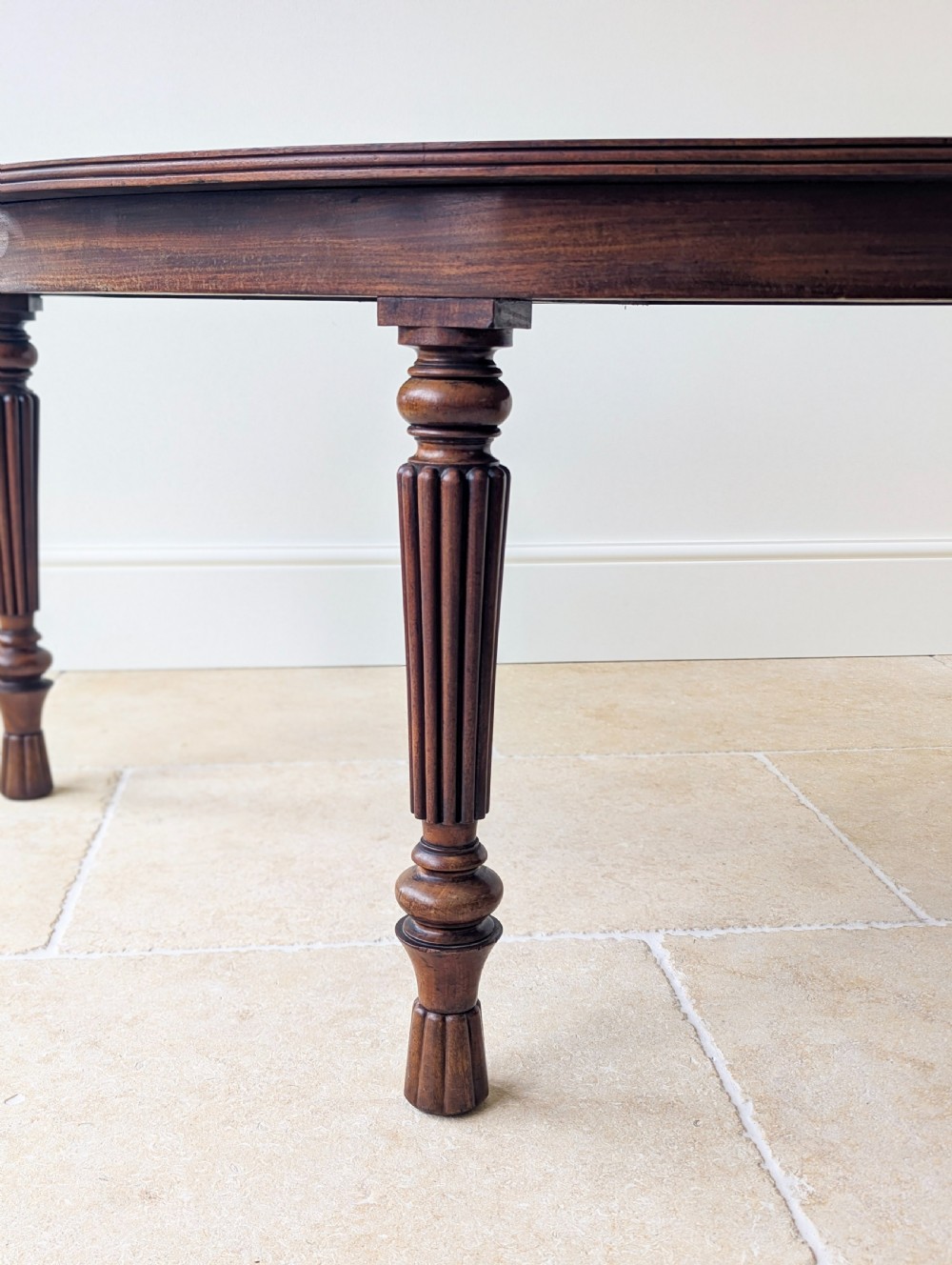 An antique Victorian demilune mahogany console table featuring a semi-circular top supported by three turned and reeded legs. View IV