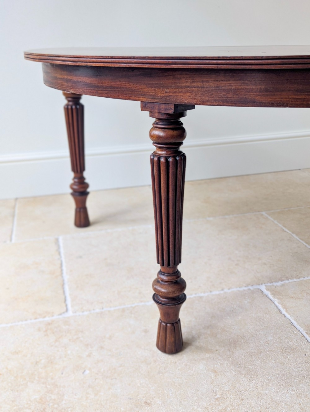 An antique Victorian demilune mahogany console table featuring a semi-circular top supported by three turned and reeded legs. View VIII