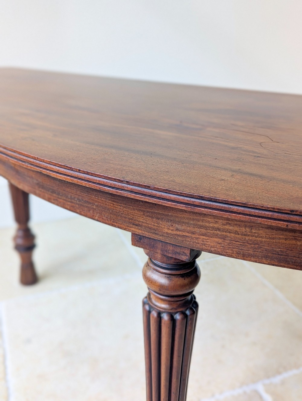 An antique Victorian demilune mahogany console table featuring a semi-circular top supported by three turned and reeded legs. View X
