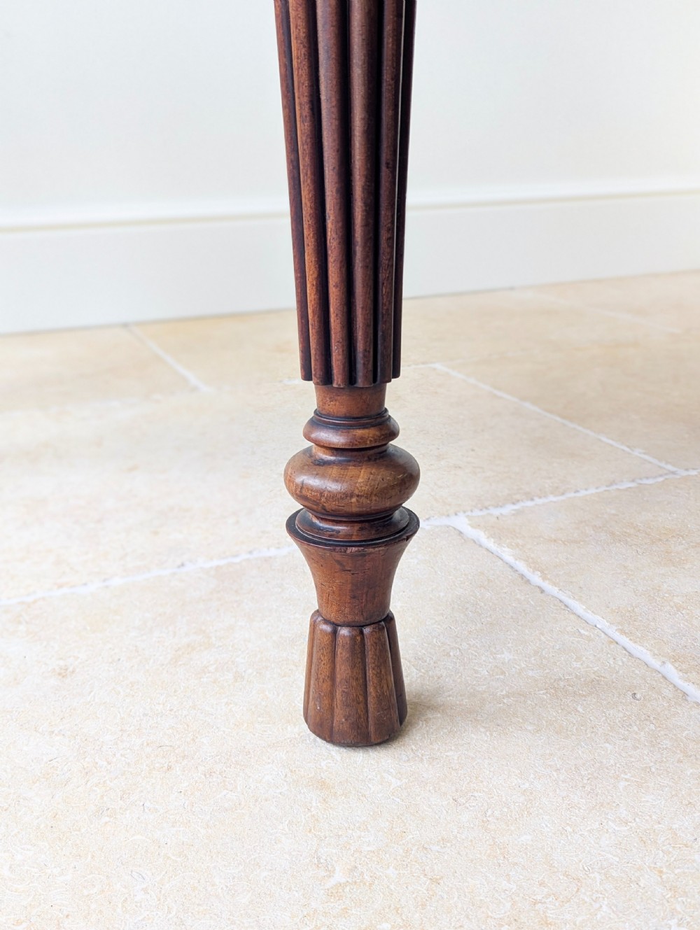 An antique Victorian demilune mahogany console table featuring a semi-circular top supported by three turned and reeded legs. View XII