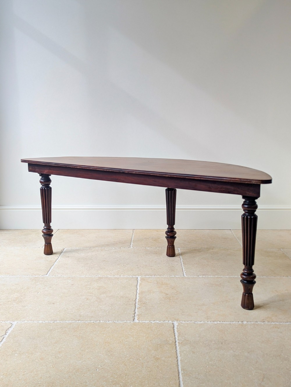 An antique Victorian demilune mahogany console table featuring a semi-circular top supported by three turned and reeded legs. View XVII