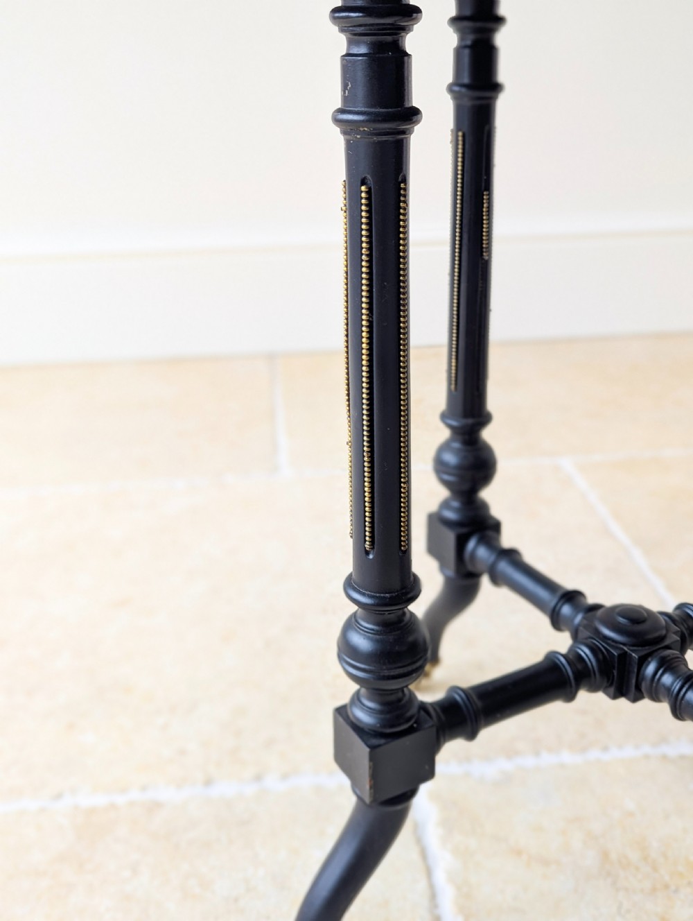 A late Victorian ebonised octagonal occasional table featuring turned legs, gilt highlights, cross stretchers, and brass castors. View VIII