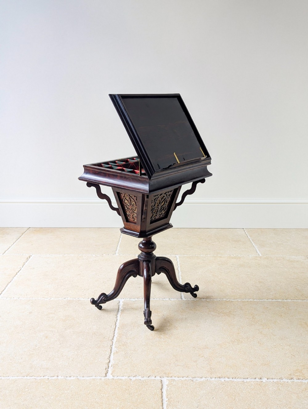 A dark brown rosewood Victorian sewing and reading table featuring an adjustable slanted lid with brass page holders, carved fretwork sides, a turned pedestal column, and four scrolled feet. View IV