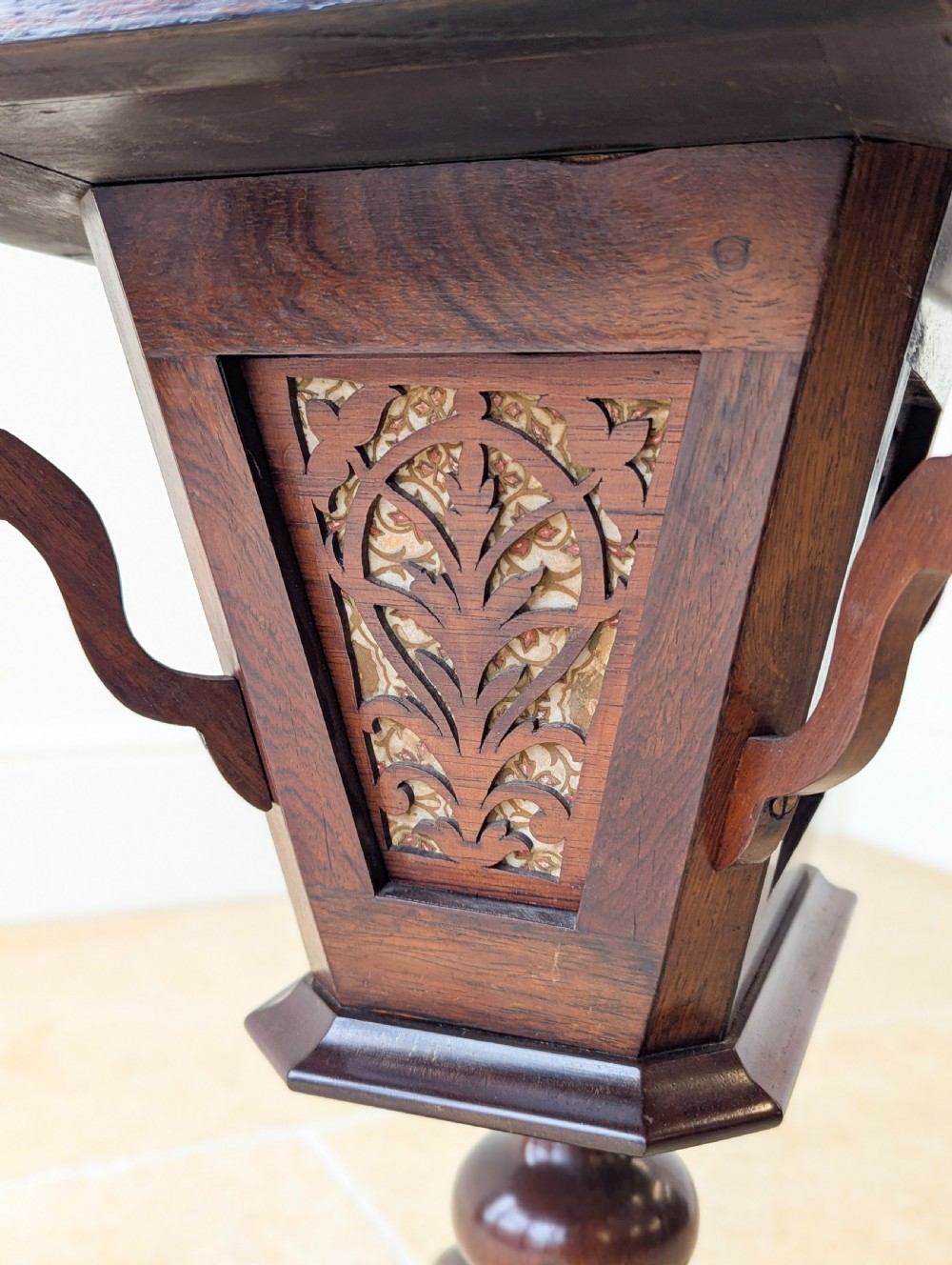 A dark brown rosewood Victorian sewing and reading table featuring an adjustable slanted lid with brass page holders, carved fretwork sides, a turned pedestal column, and four scrolled feet. View VIII